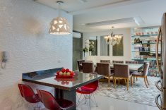 Na cozinha, o amadeirado prevalece em meio a toques de vermelho, como nas cadeiras Marili Decor